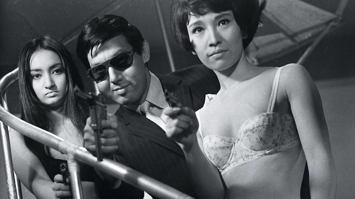 Joe Shishido, flanked by women in underwear, aiming a gun in Branded to Kill - movies like tokyo vice