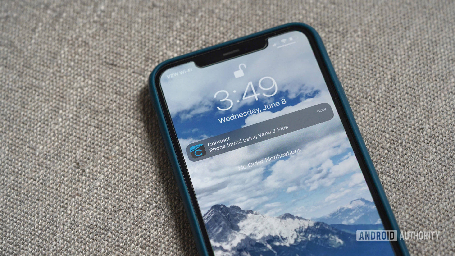 The iPhone 11 rests on a gray sofa, and displays the banner notification that it was found with a Garmin Venu 2 Plus.