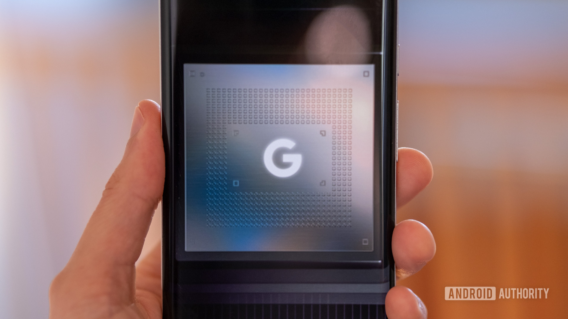 A phone with the Google Tensor chip logo on hand