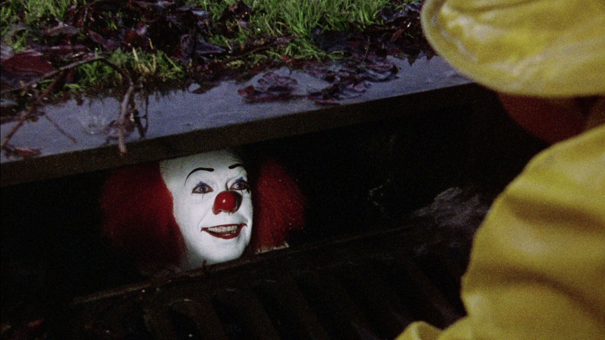 Pennywise smiles from inside a gutter in It 1990 - movies like stranger things