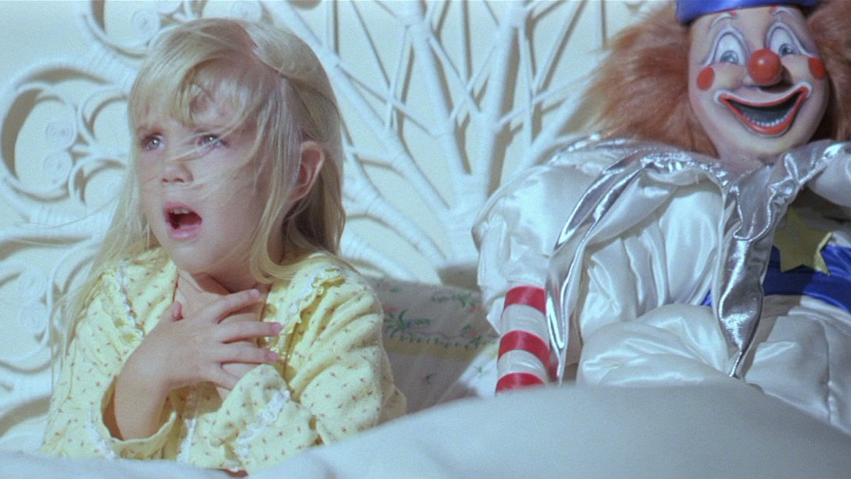 A girl sits next to a clown dummy in Poltergeist - movies that inspires stranger things
