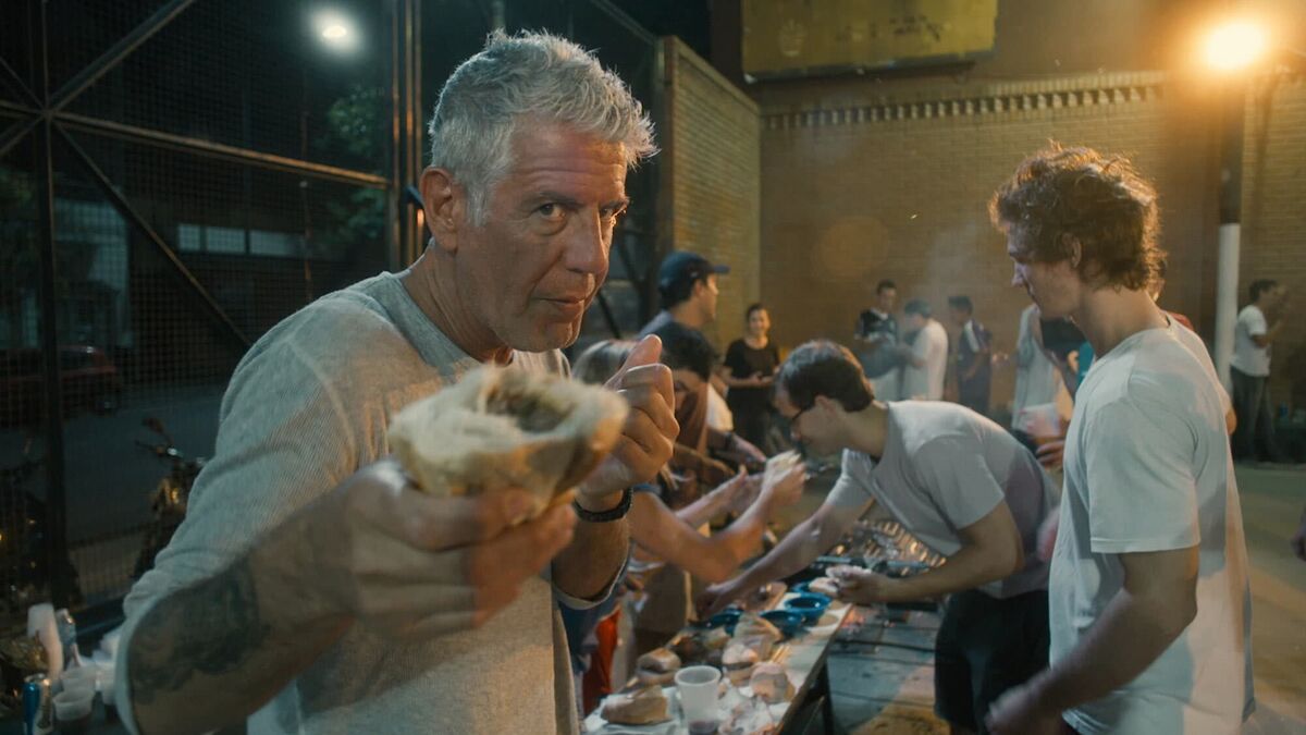 Anthony Bourdain holding up food in Roadrunner A Film About Anthony Bourdain