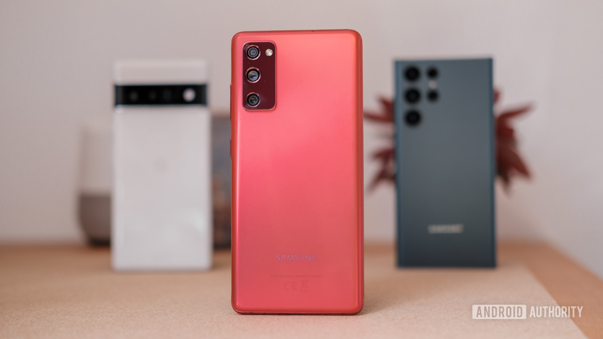 Samsung Galaxy S20 FE berwarna merah, dengan S22 Ultra dan Pixel 6 di latar belakang.