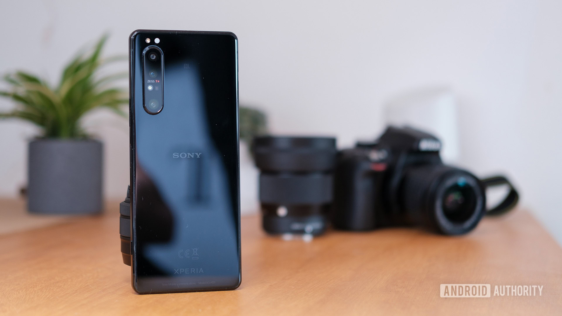 Sony Xperia phone standing upright next to a Nikon DSLR camera 