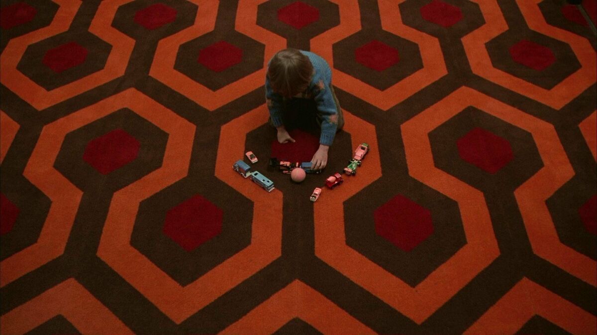 Danny Torrence plays with toys on a carpet in The Shining