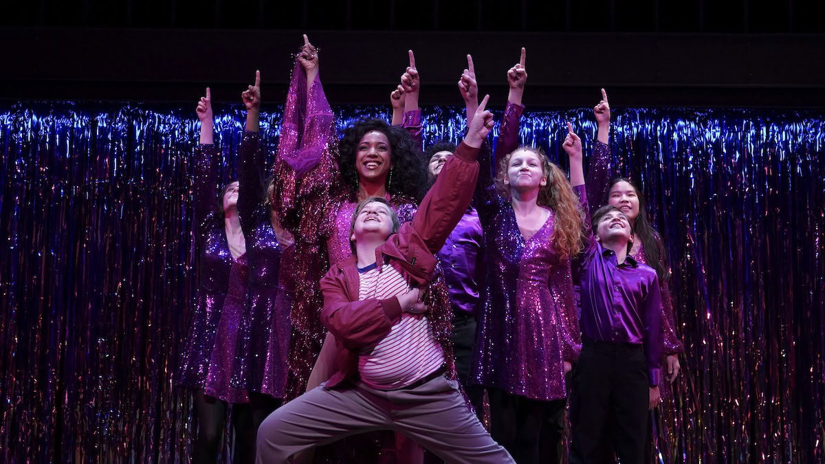 A kid on stage with backup dancers in Trevor The Musical