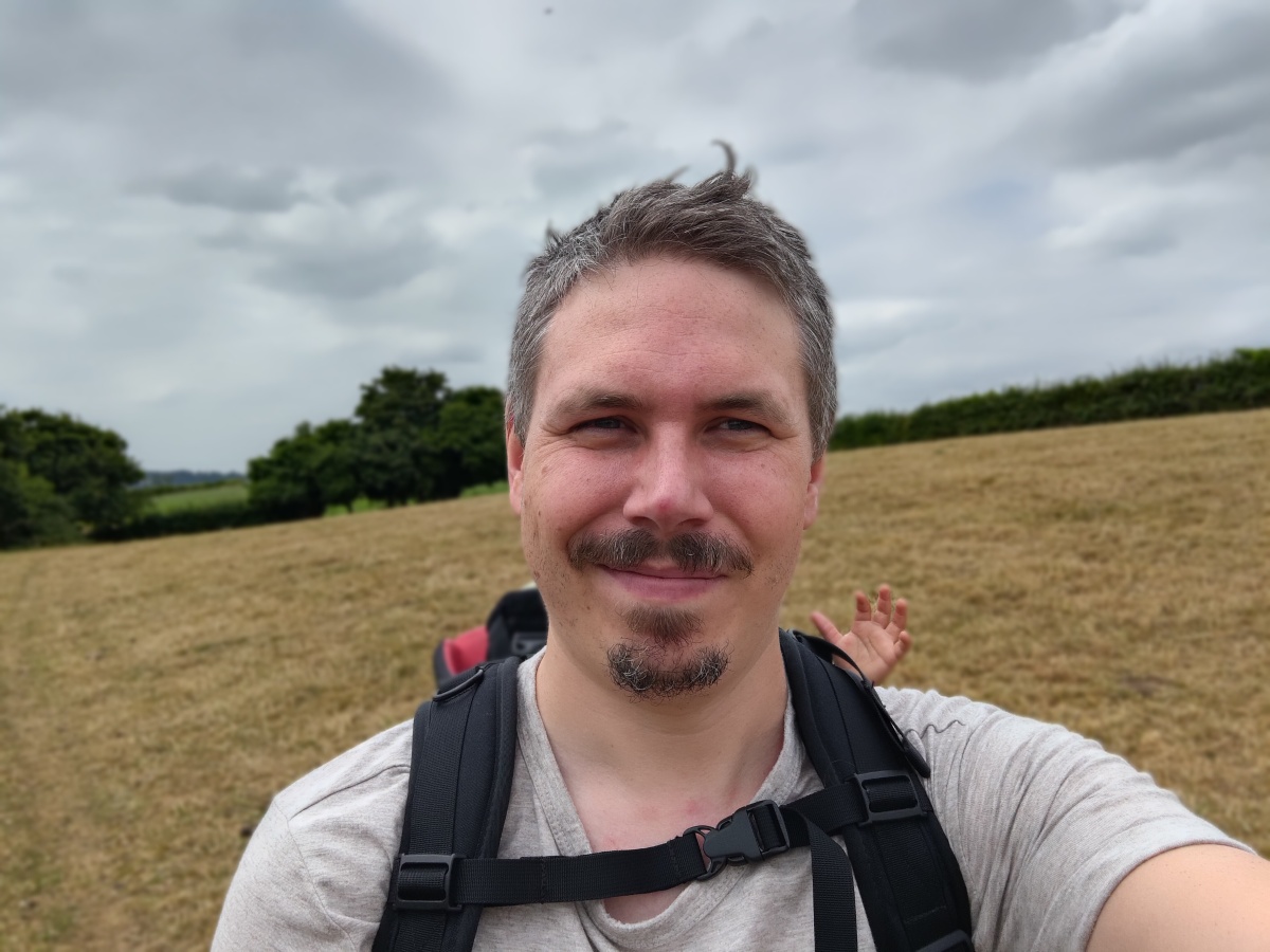 ASUS Zenfone 9 camera sample selfie portrait outdoors of a man with facial hair wearing a light colored tshirt, his ruckstrack straps visible