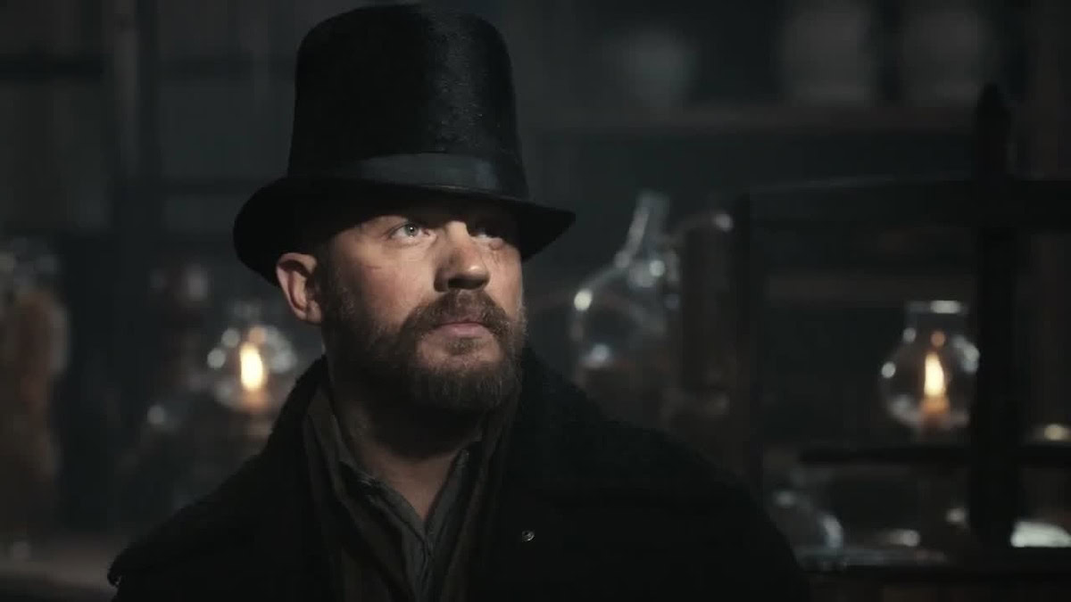 Tom Hardy, wearing a top had and standing in shadows, in Taboo - shows like Peaky Blinders