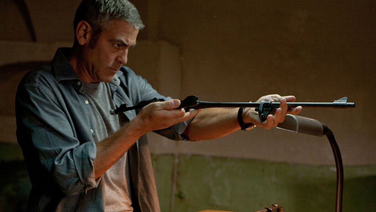 George Clooney holds a rifle in The American - best movies leaving Hulu