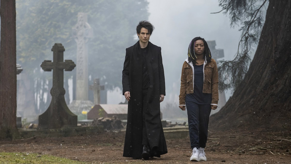 Un hombre y una mujer joven caminan por un cementerio en The Sandman, nuevo en Netflix en agosto