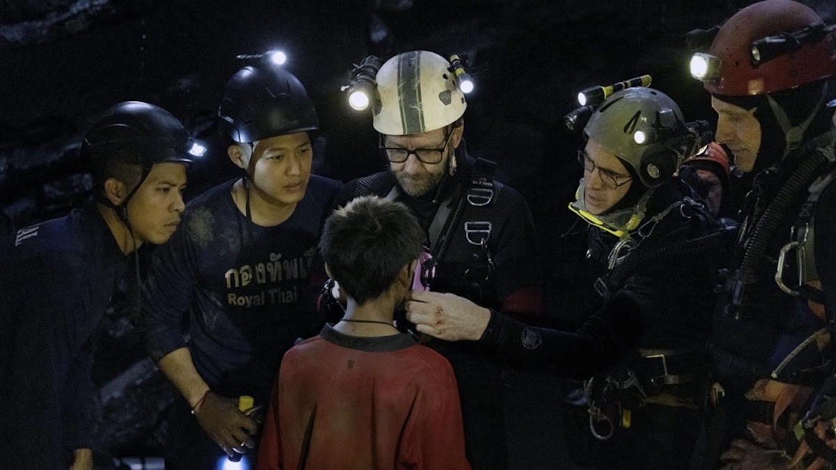 A group of divers stands with a kid in Thirteen Lives