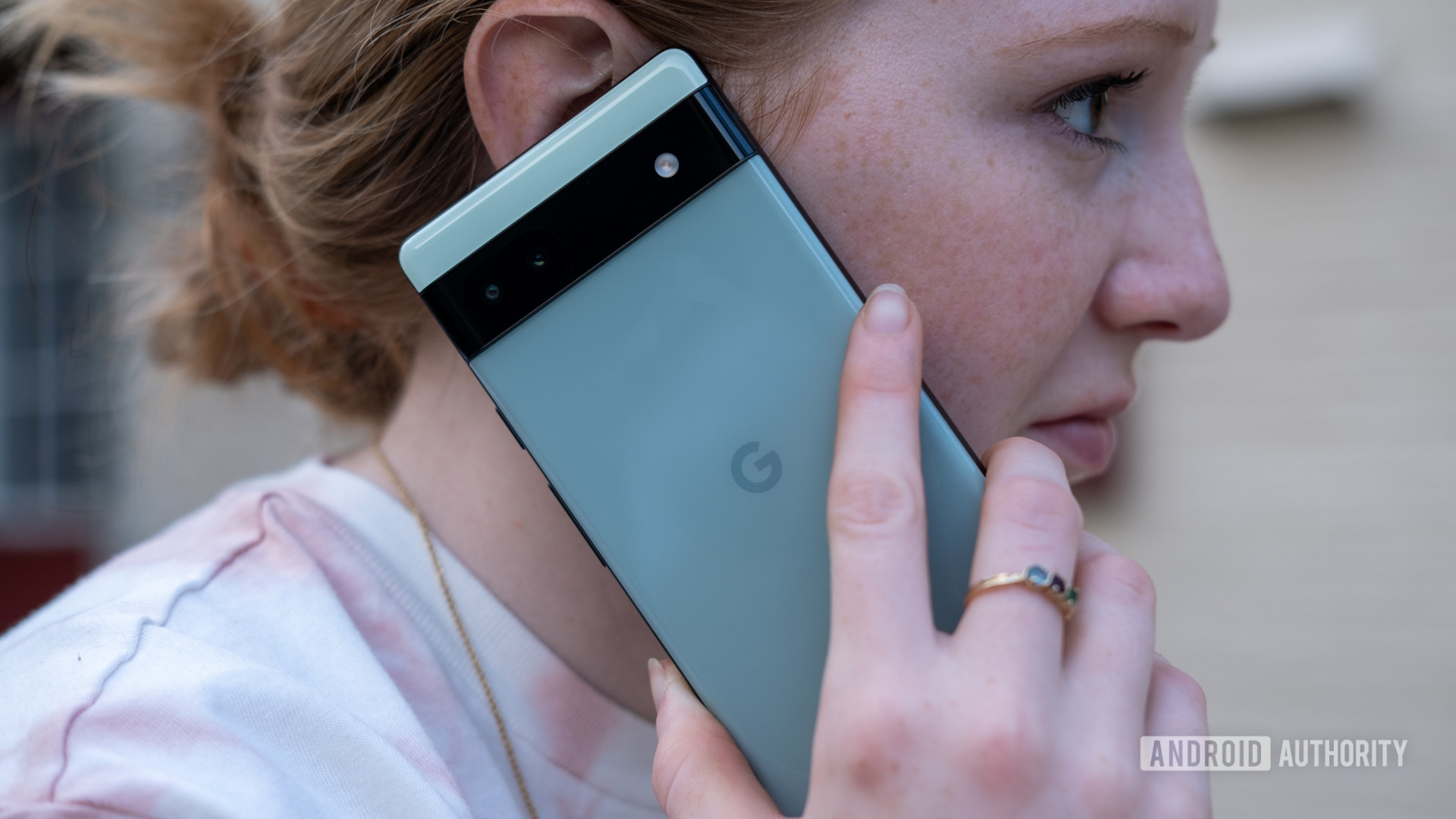A woman holds the google pixel 6a up to her ear