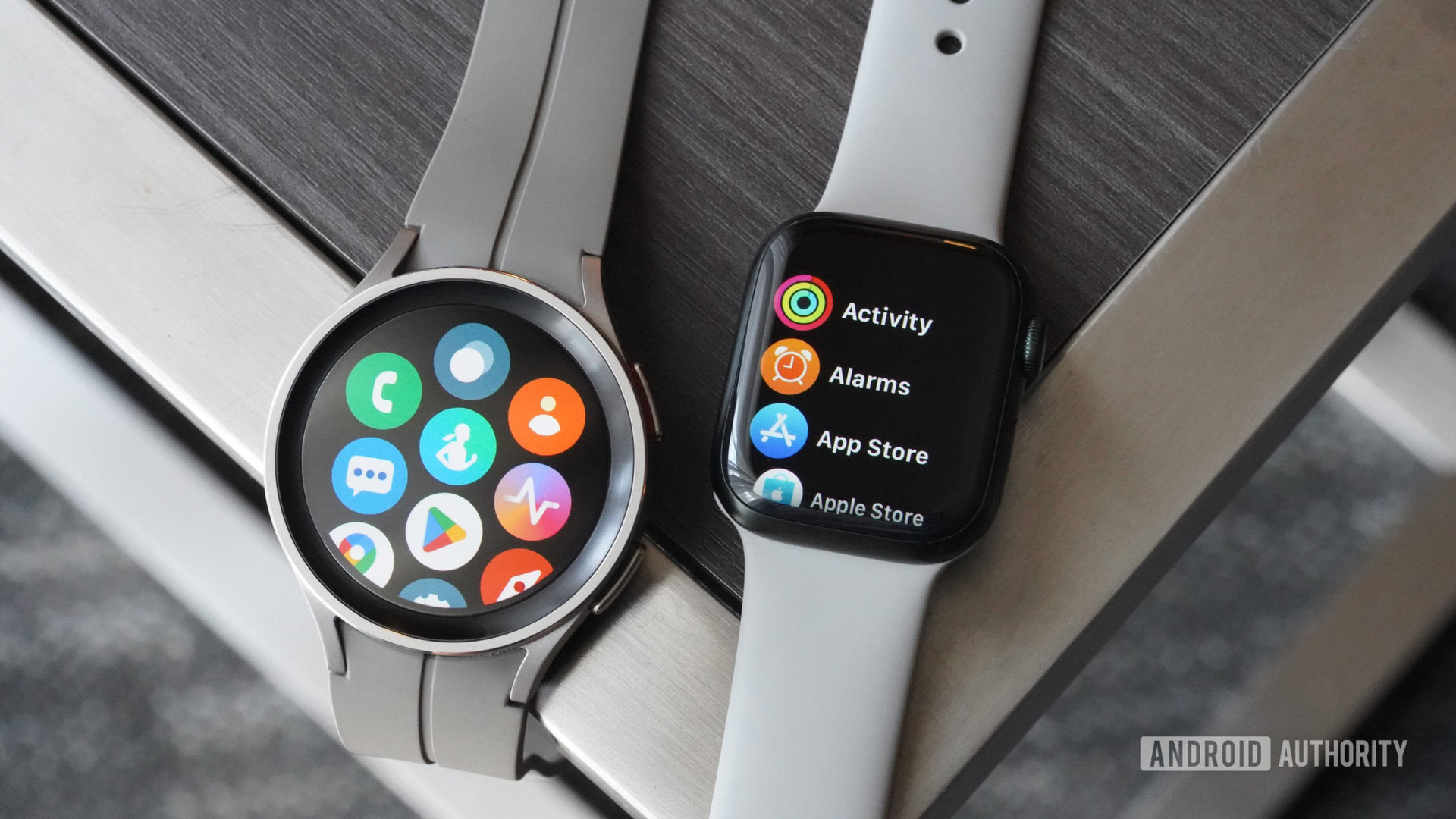 An Apple Watch and a Galaxy Watch 5 Pro rest side by side on a metallic table.