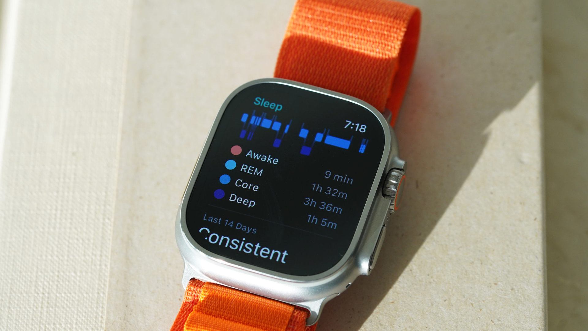 An Apple Watch Ultra rests on a book displaying a user's sleep stages.