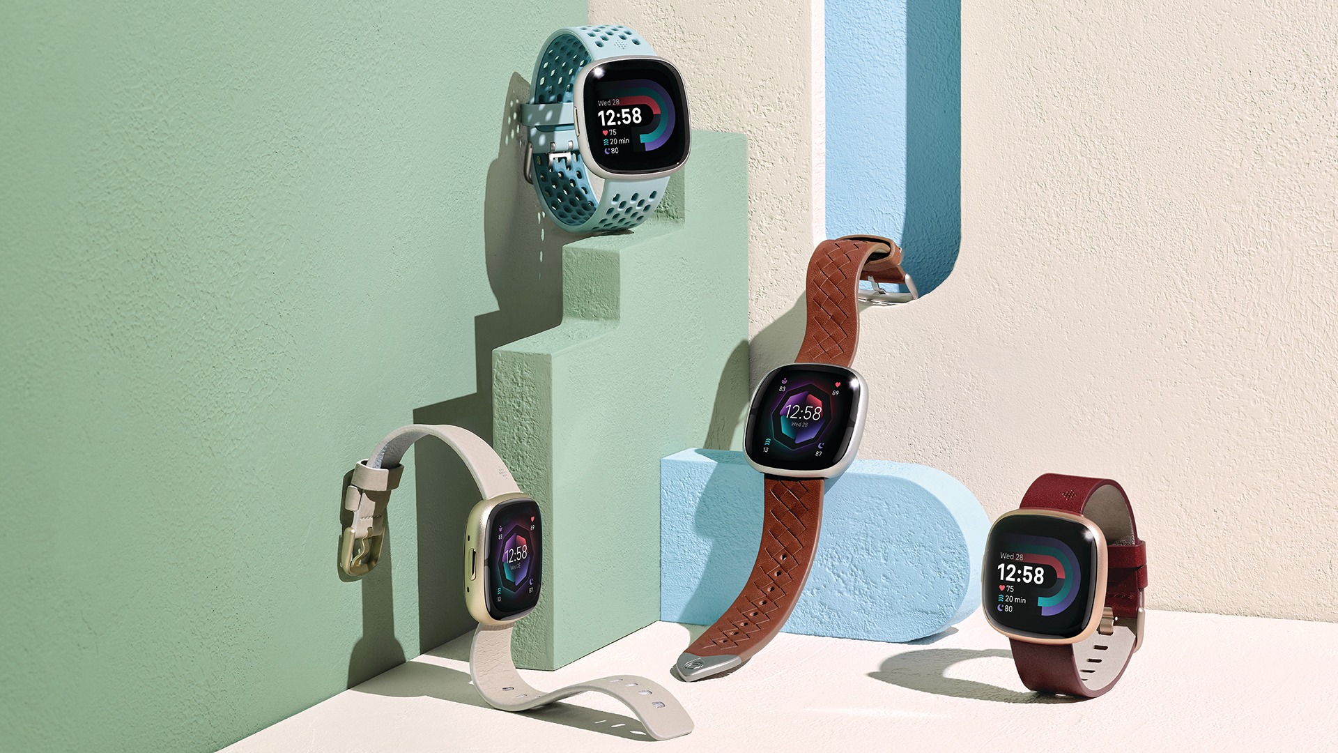 Fitbit Sense 2 dan Fitbit Versa 4 Hero Image dengan empat jam tangan di antara wallpaper warna-warni