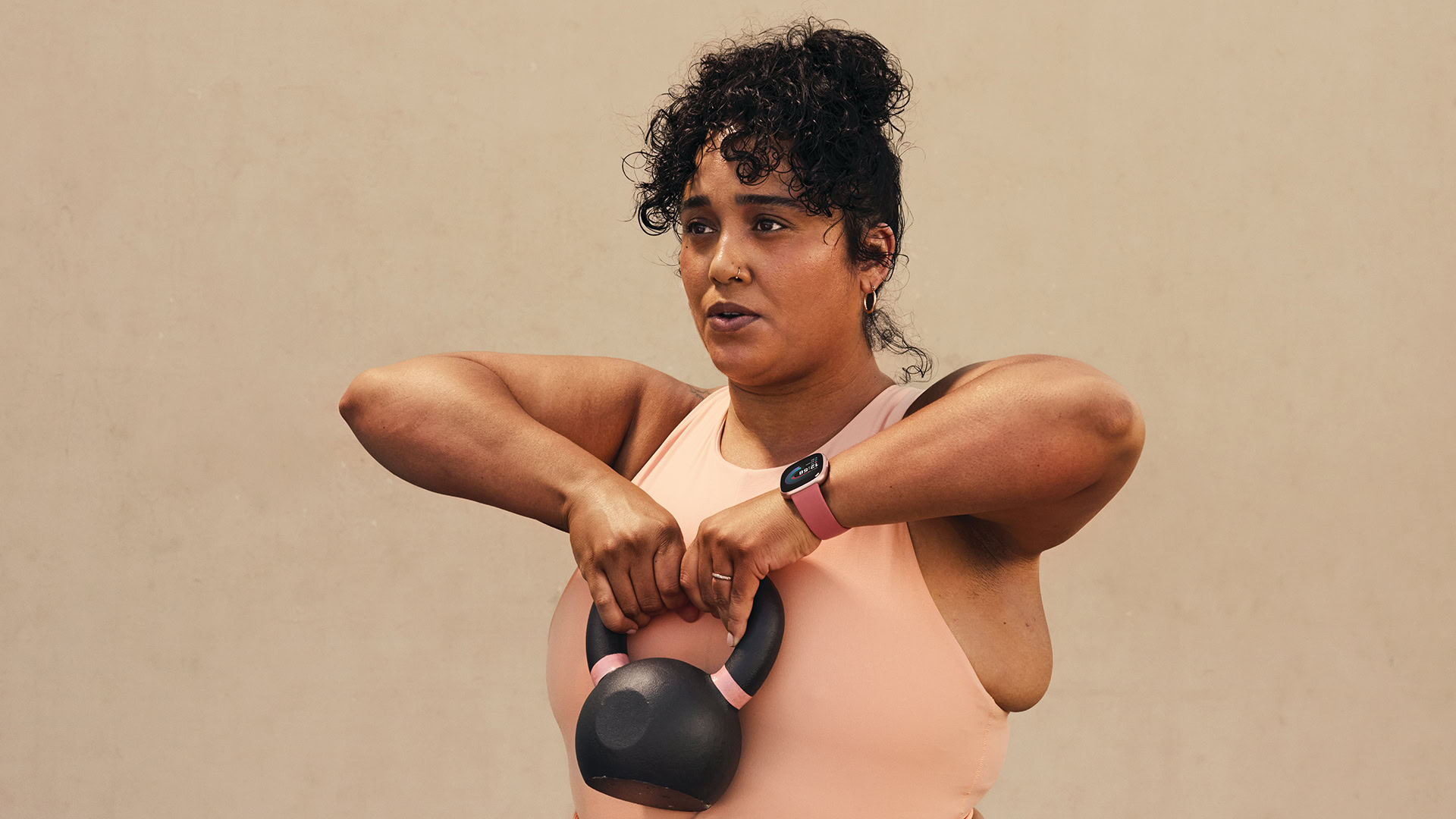 Fitbit Versa 4 on Womans Wrist As She Lifts A Dumbbell