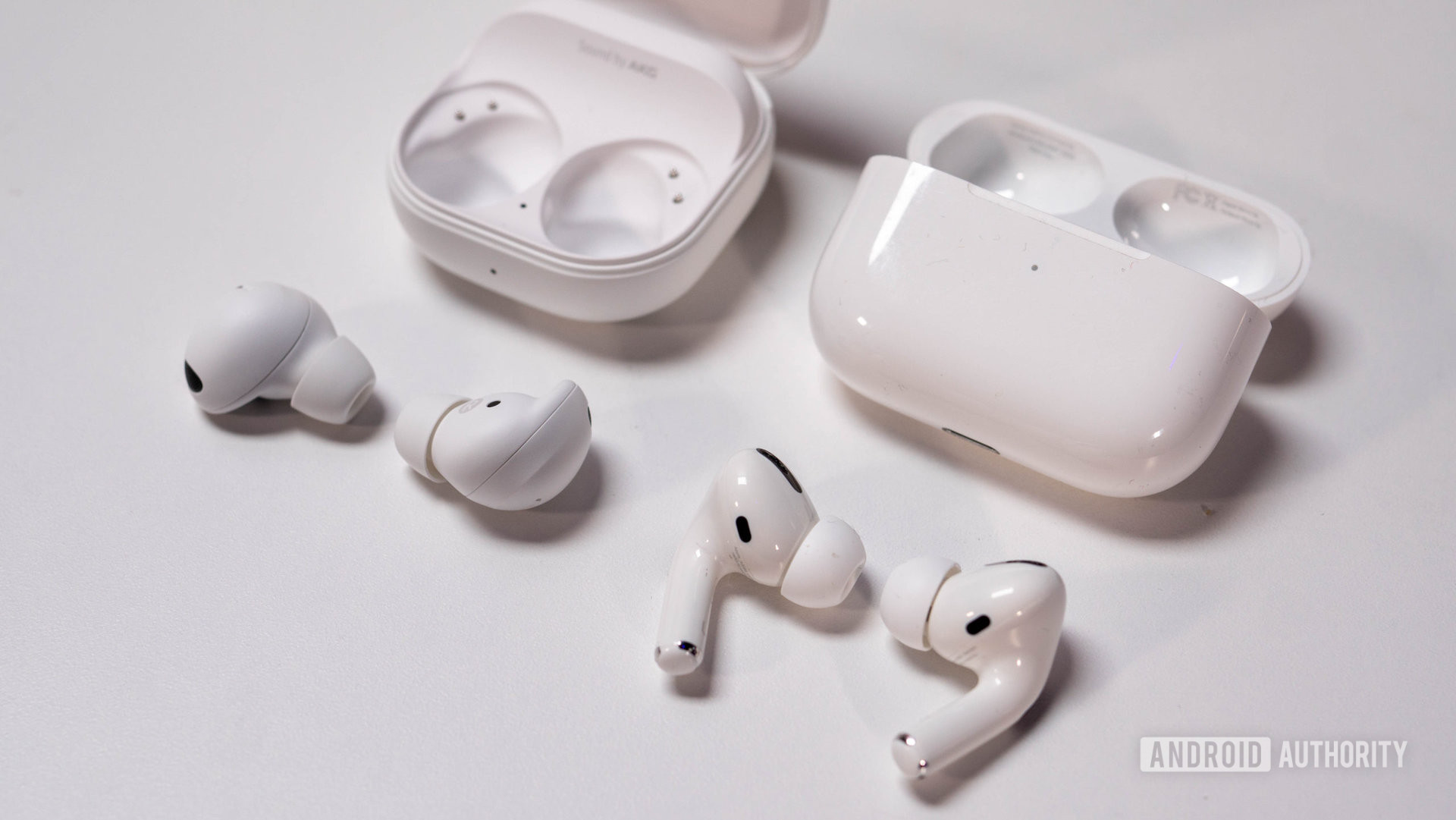 Samsung Galaxy Buds 2 Pro vs AirPods Pro laying next to charging case closeup