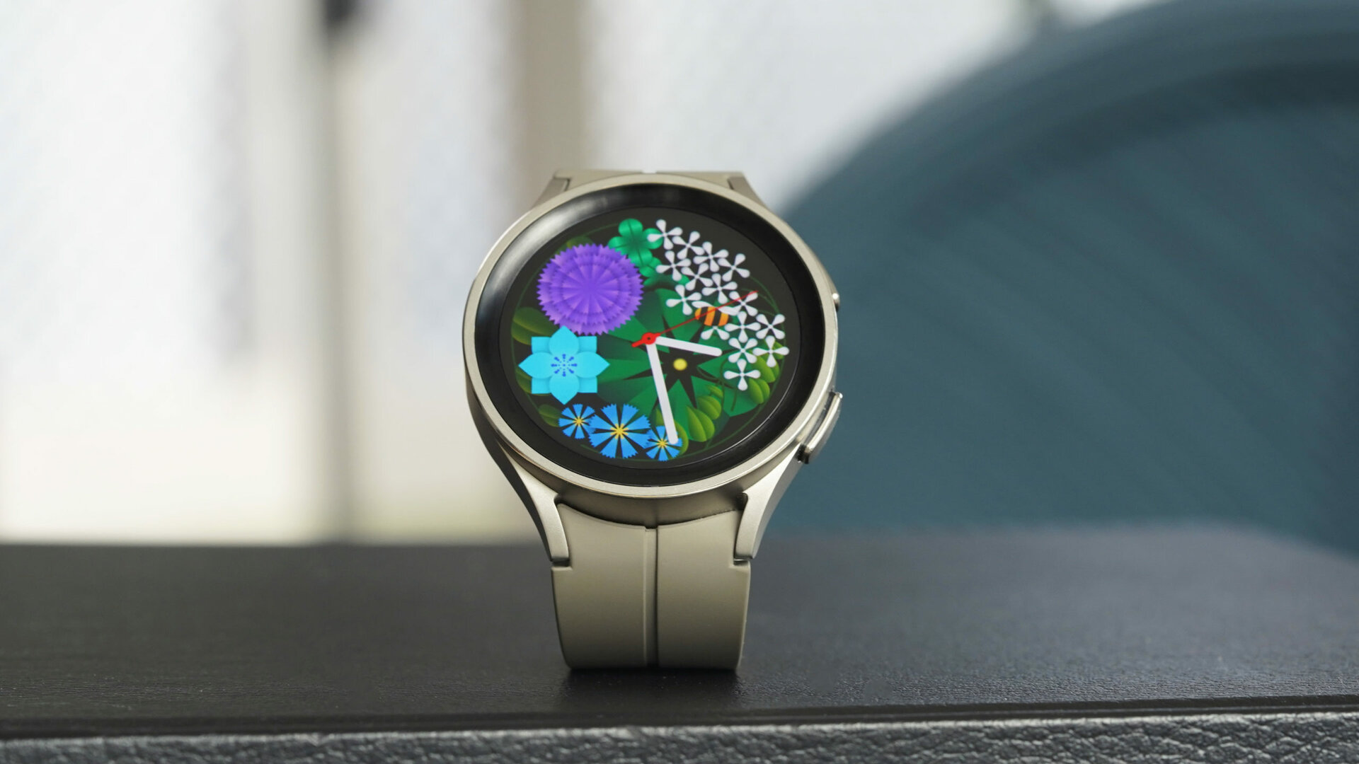 A Samsung Galaxy Watch 5 Pro displays a vibrant floral watch face.