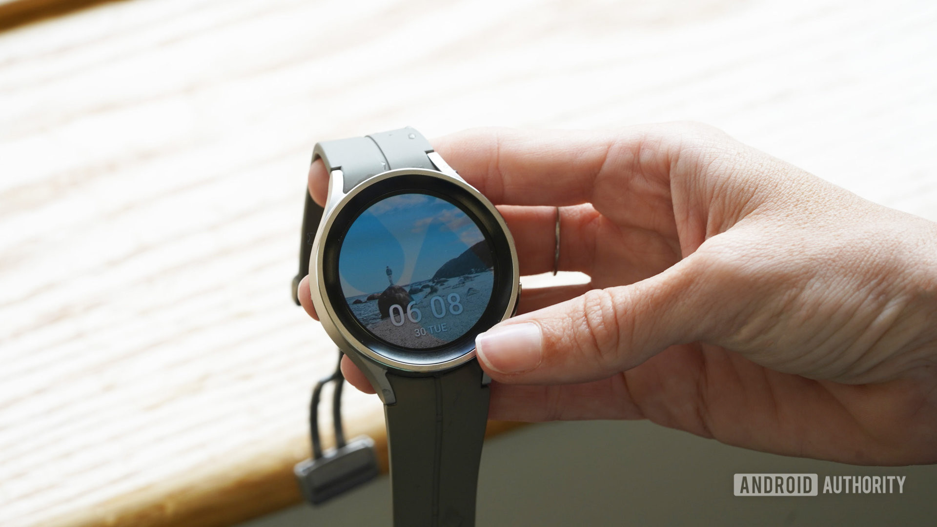 A Samsung Galaxy Watch 5 Pro in a user's hand displays the water Lock Screen.
