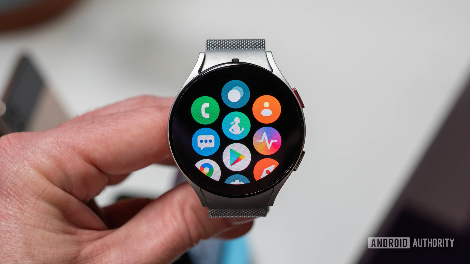 Samsung Galaxy Watch 5 in silver color with metal bracelet in hand showing app picker
