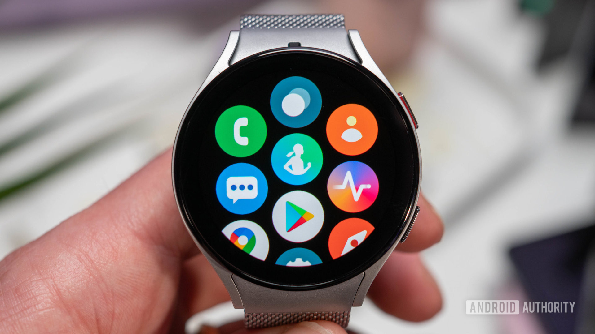 Samsung Galaxy Watch 5 in silver color with metal bracelet in hand showing apps closeup