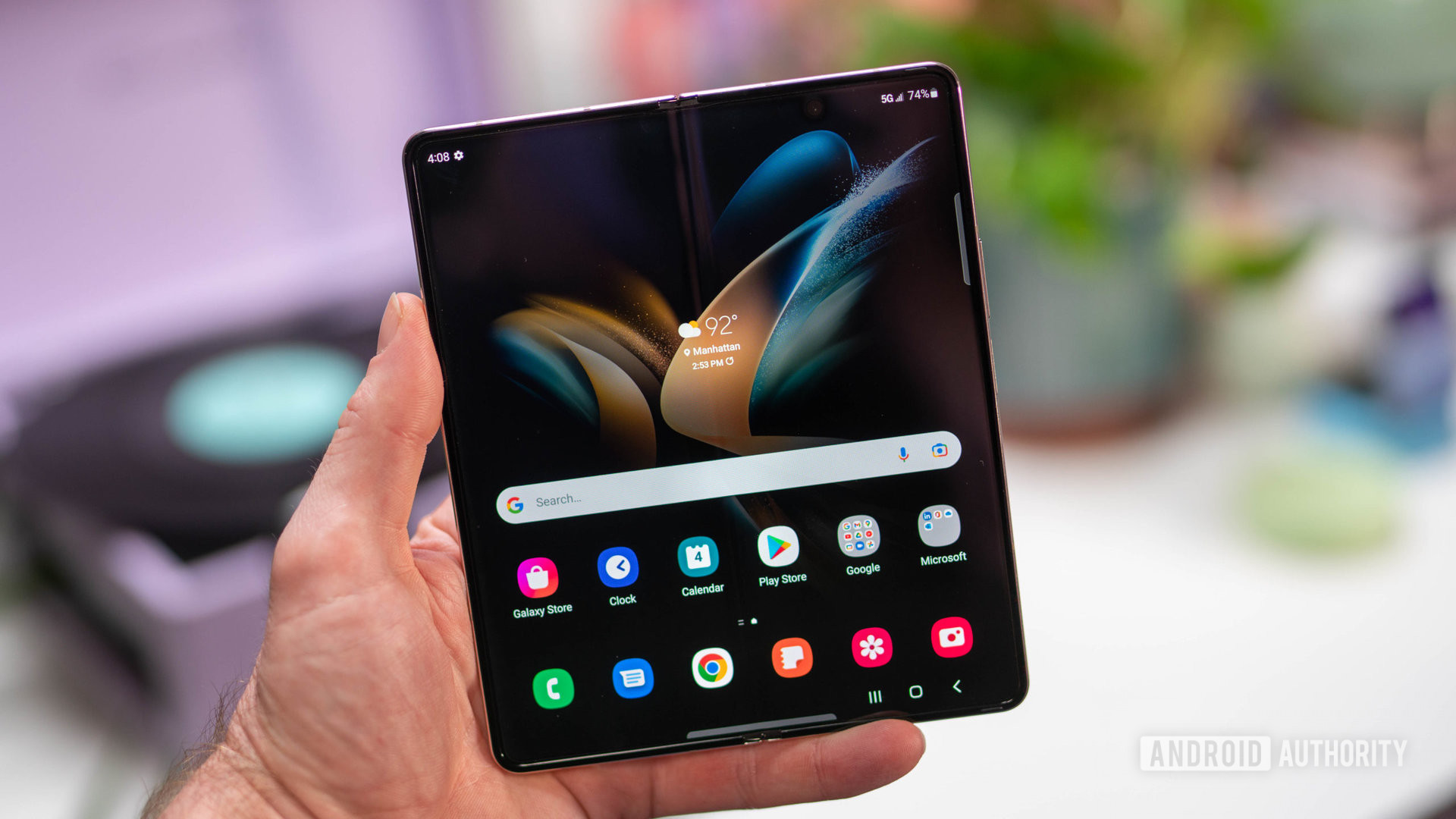 Samsung Galaxy Z Fold 4 open in hand showing home screen