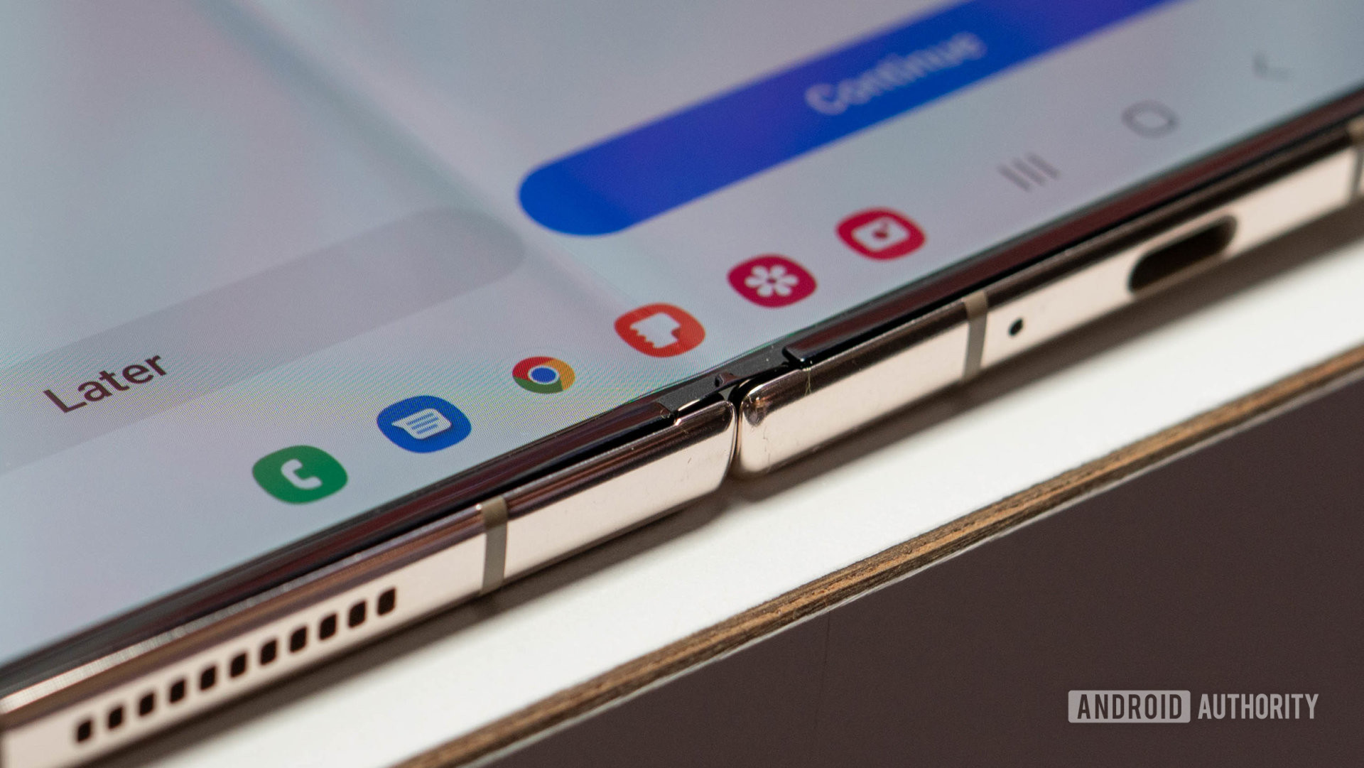 „Samsung Galaxy Z Fold 4“ atidarytas gulėdamas ant stalo, kuriame rodomos vyrių detalės ir programų doko užduočių juosta