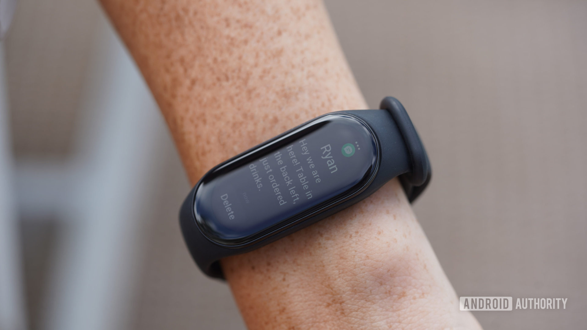 A Xiaomi Mi Band 7 displays a text notification from the user on the screen.