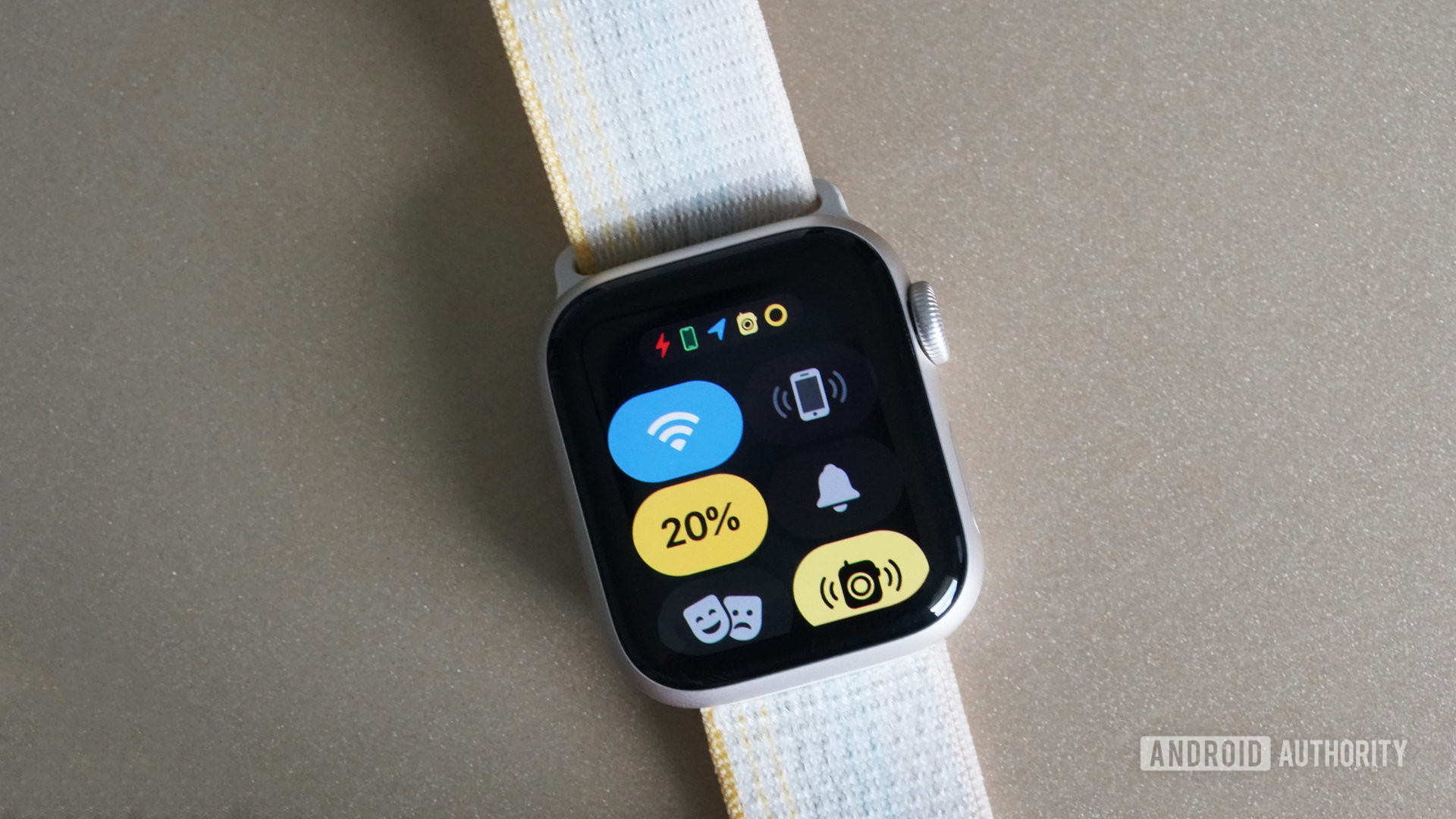 An Apple Watch SE 2 rests on a tan surface displaying the quick panel menu.