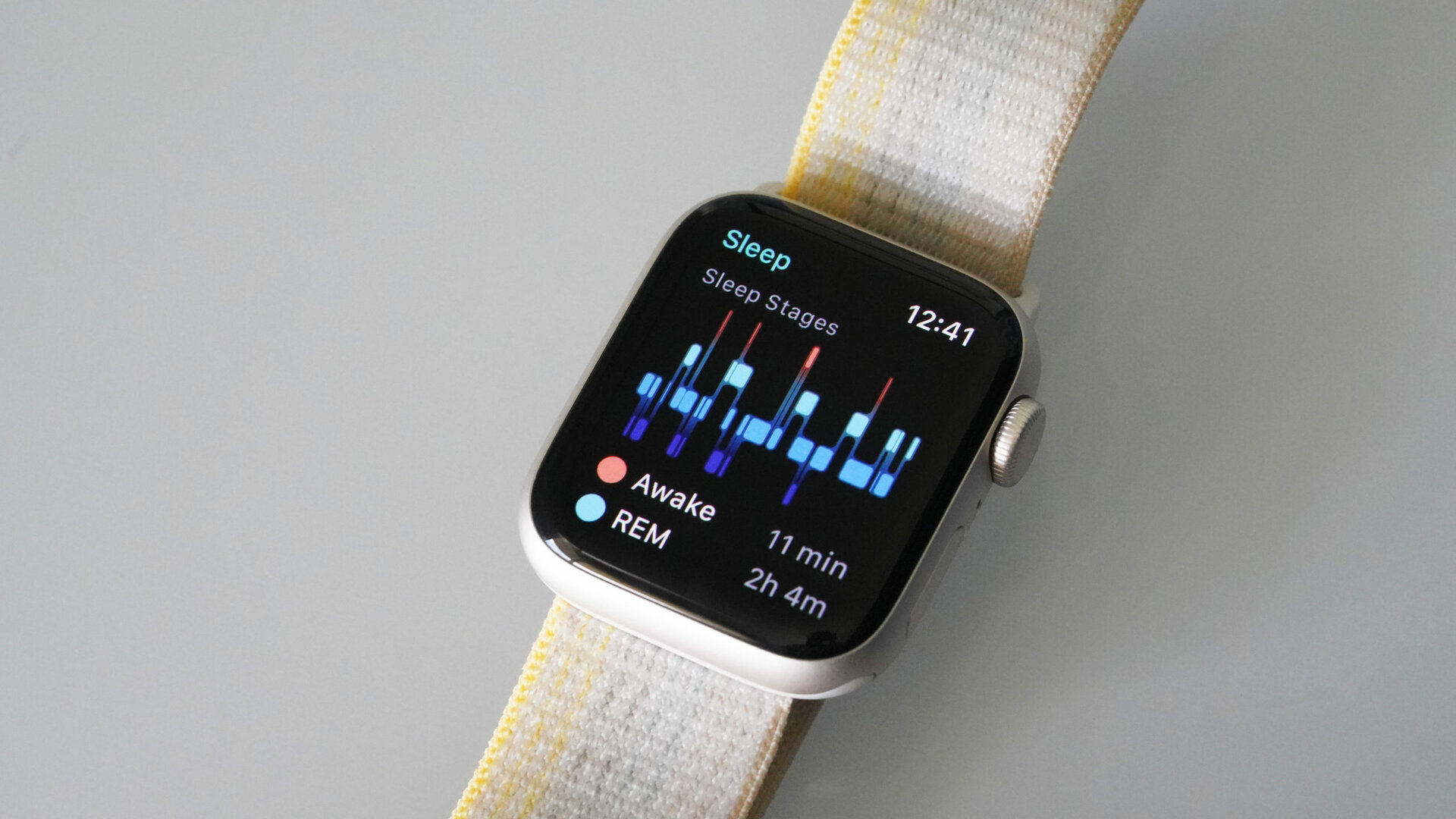 An Apple Watch SE 2 rests on a white surface displaying a user's sleep stages.