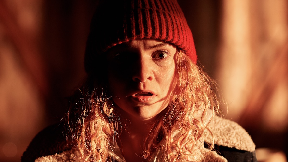 A woman in a red toque looks into the camera in Blow the Man Down