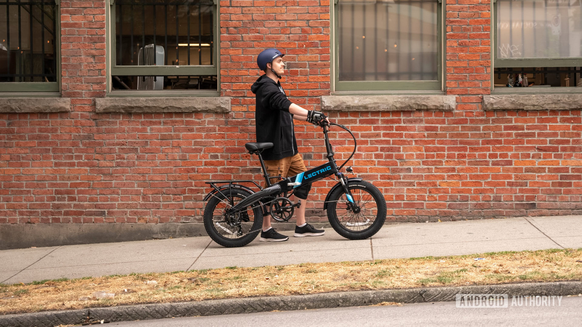 walking electric bike up hill beside brick wall