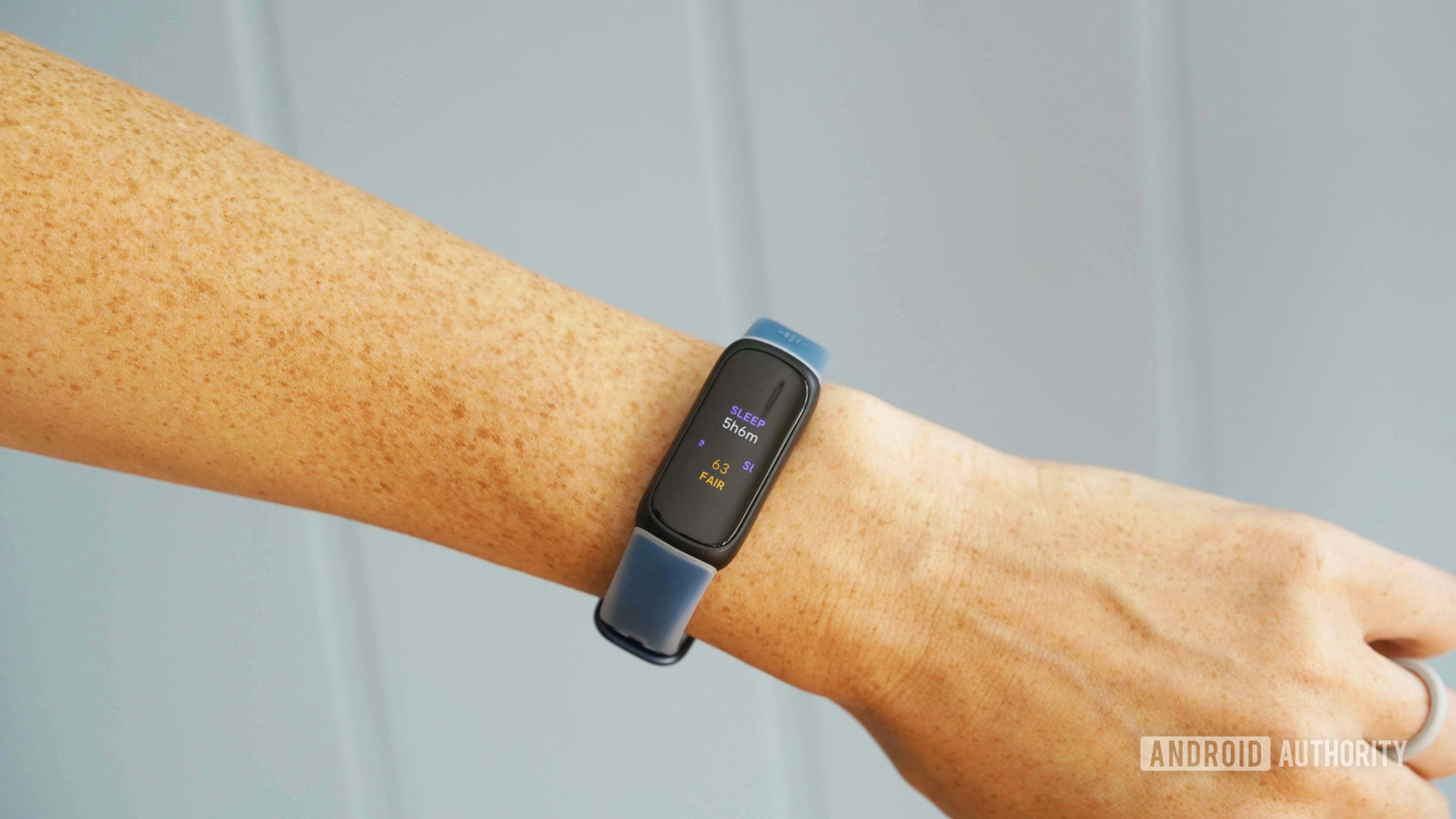 A Fitbit Inspire 3 displays a user's total sleep time and Sleep Score.
