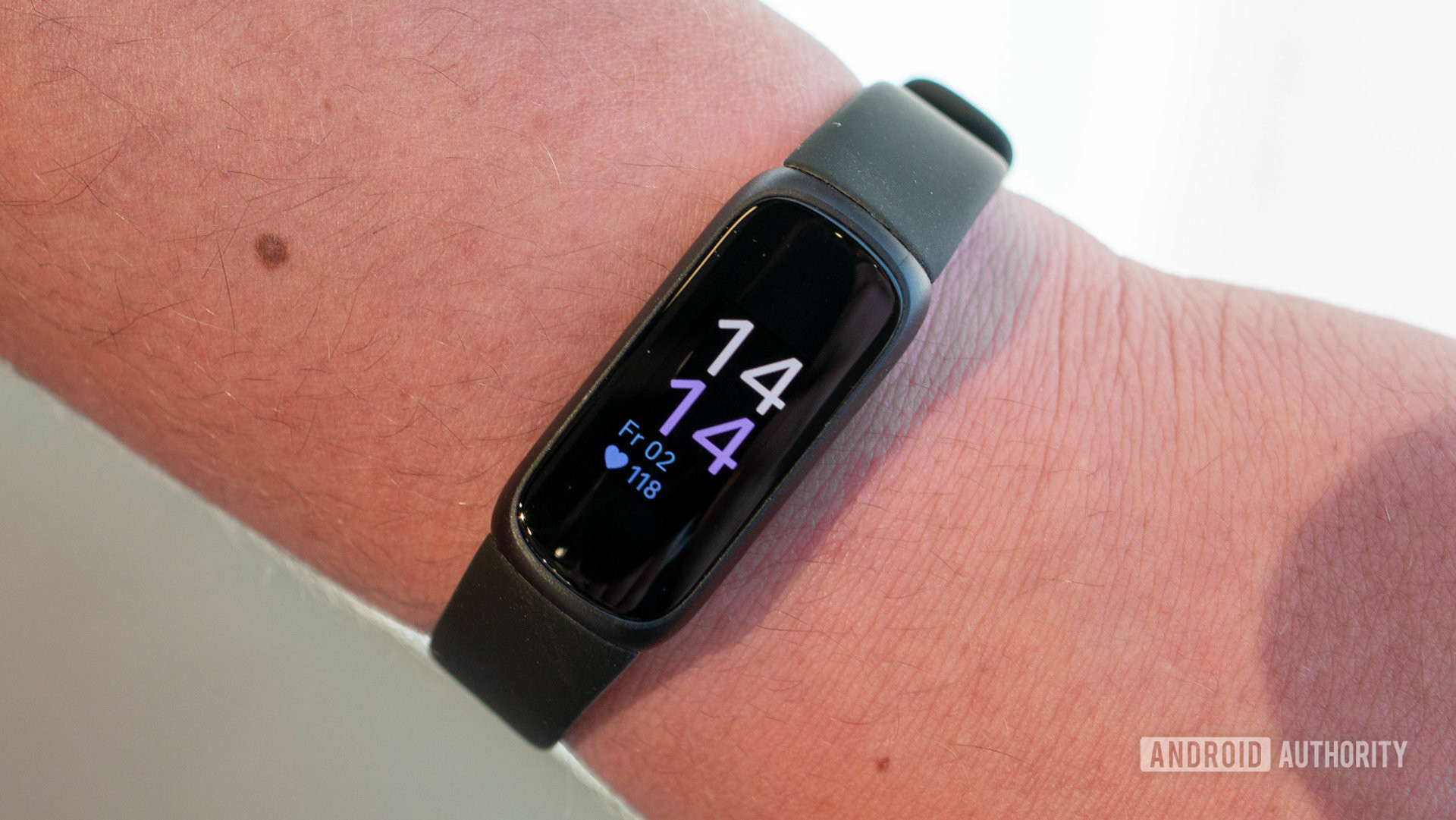 Fitbit Inspire 3 di pergelangan tangan pengguna menampilkan layar beranda.