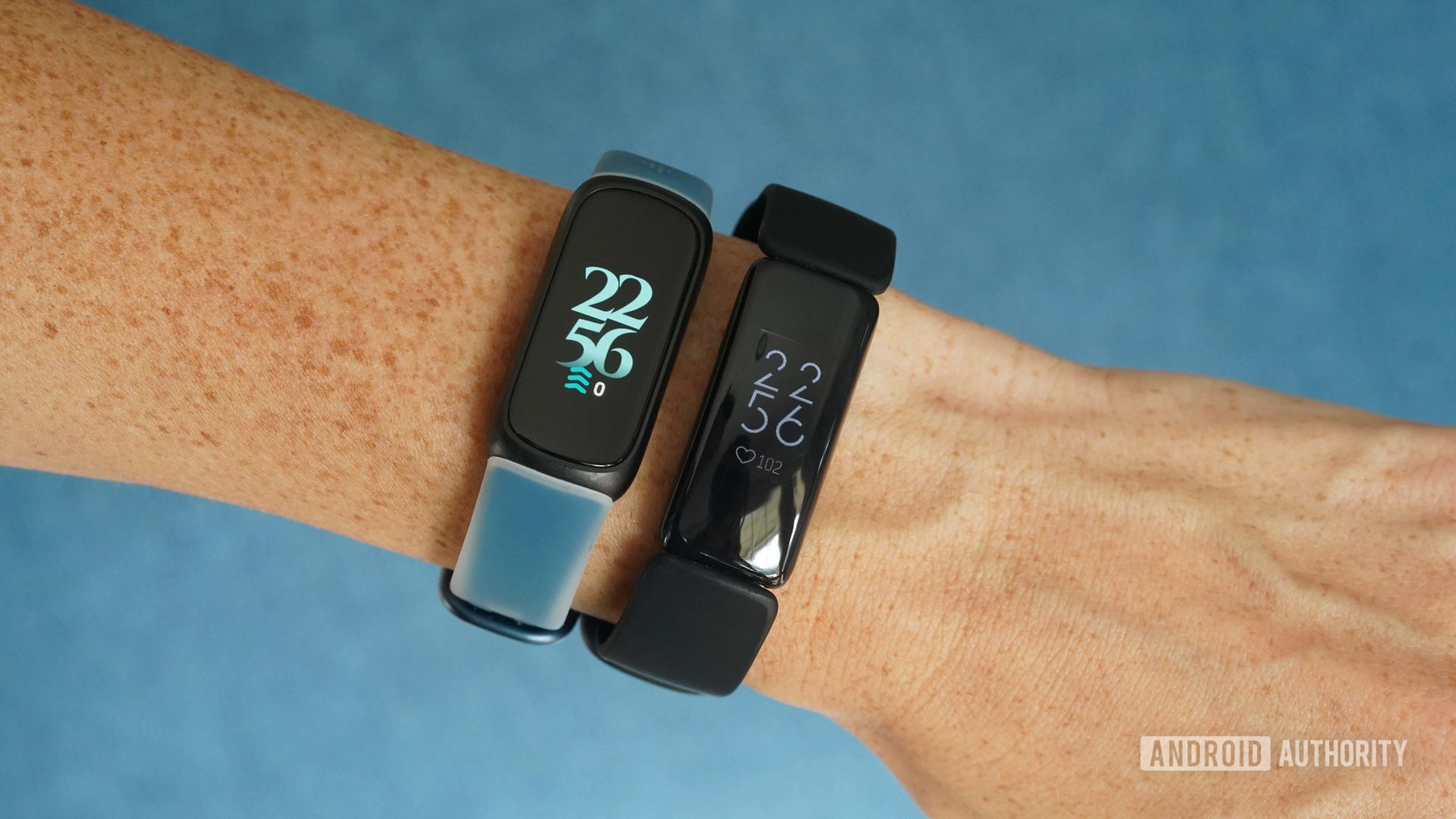 A user wears a Fitbit Inspire 3 and an Inspire 2 side by side on the same wrist.