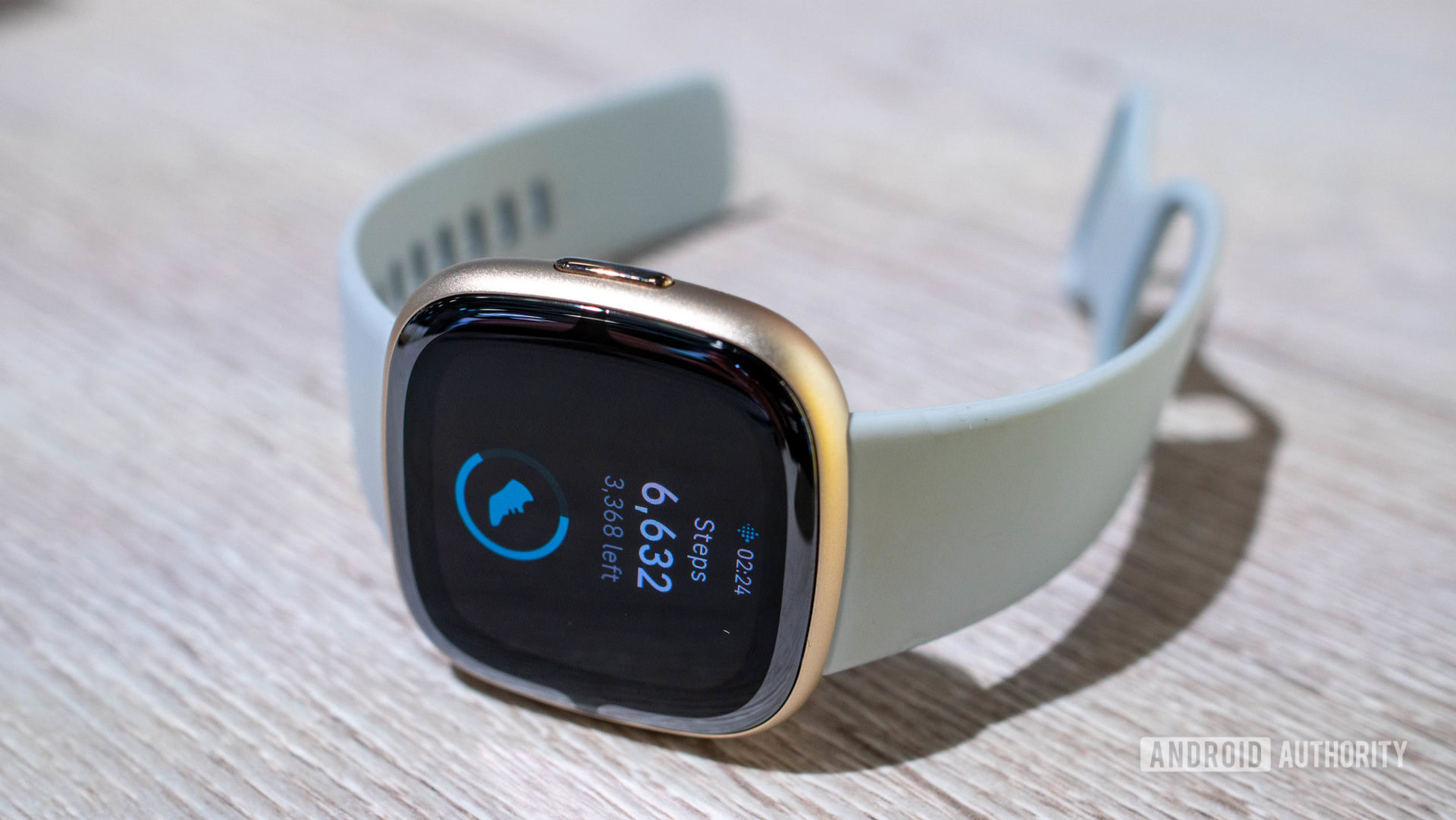 A Fitbit Sense 2 displays a user's step count.