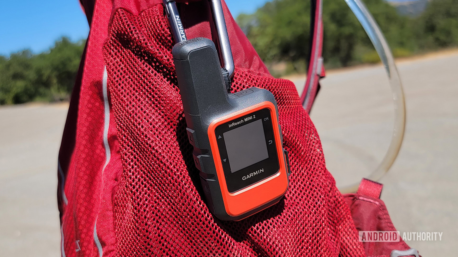 Garmin InReach Mini 2 strapped to a red hiking backpack