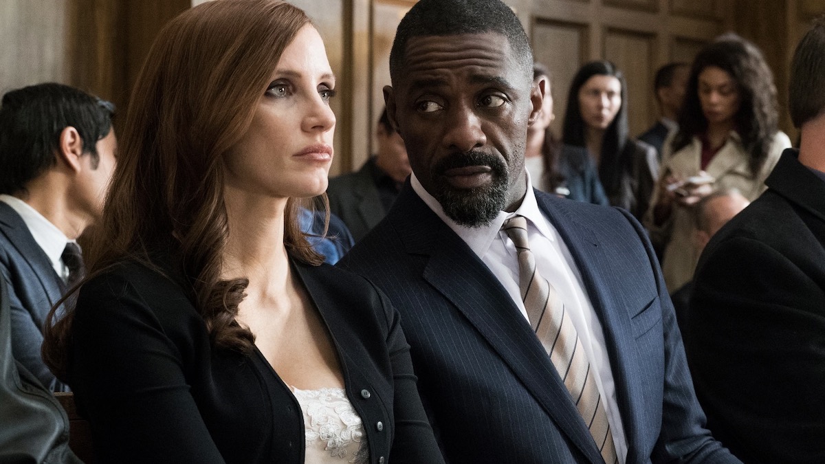 Jessica Chastain and Idris Elba sit at a table together in court in Molly's Game - best gangster movies on netflix