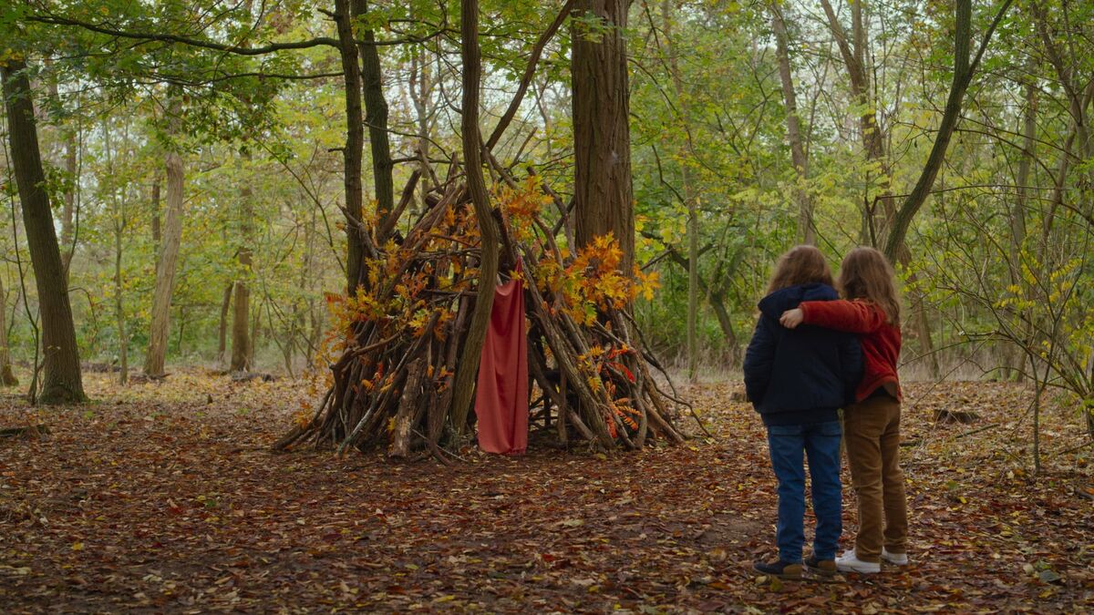 Two little girls stand in from of a tree fort in the woods in Petite Maman - best new streaming movies