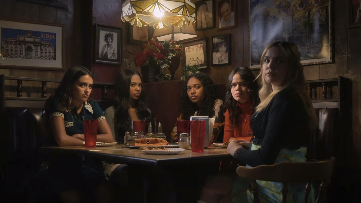 Five teens sitting in a dimly lit restaurant in Pretty Little Liars: Original Sin - Best Horror TV Shows