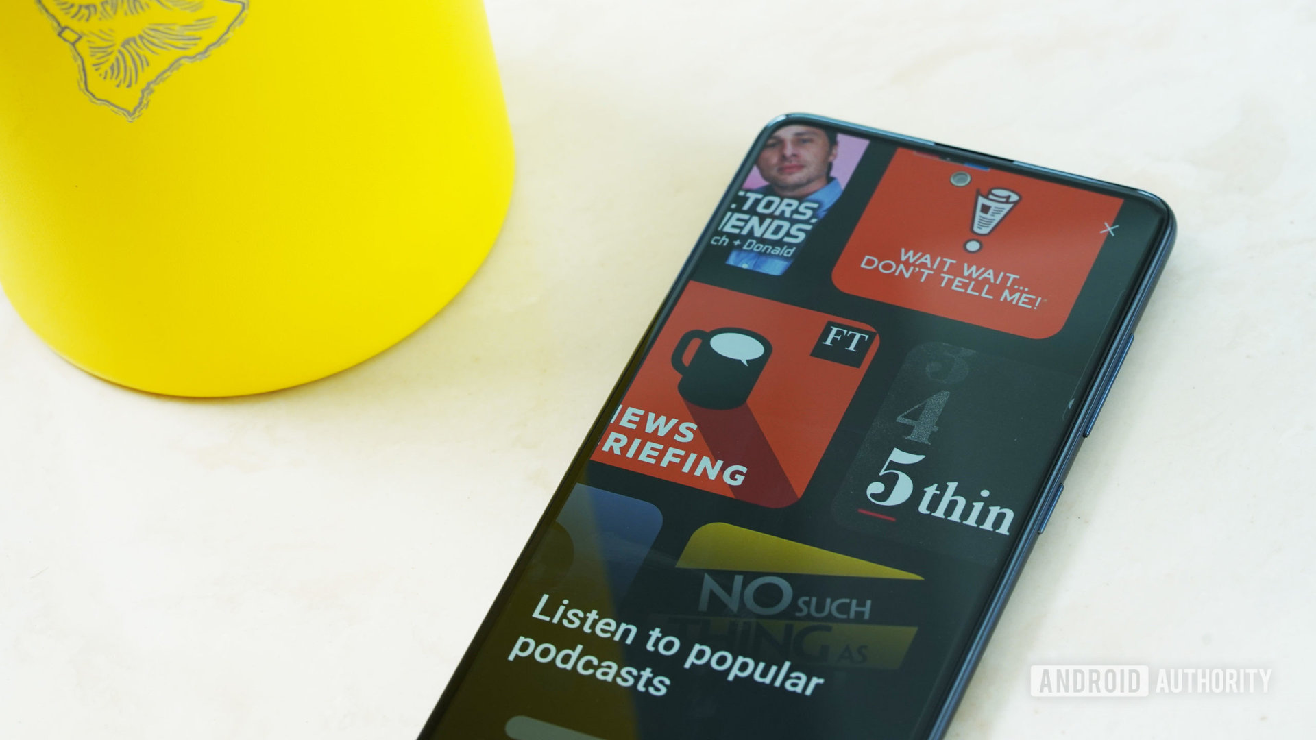 A Samsung Galaxy A51 rests on white surface displaying popular podcasts available via Samsung Free.