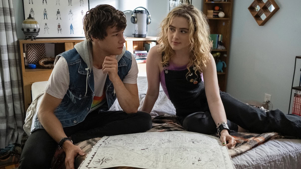 Kyle Allen y Kathryn Newton se sientan en una cama mirando un mapa en The Map of Tiny Perfect Things: películas originales de alta calidad