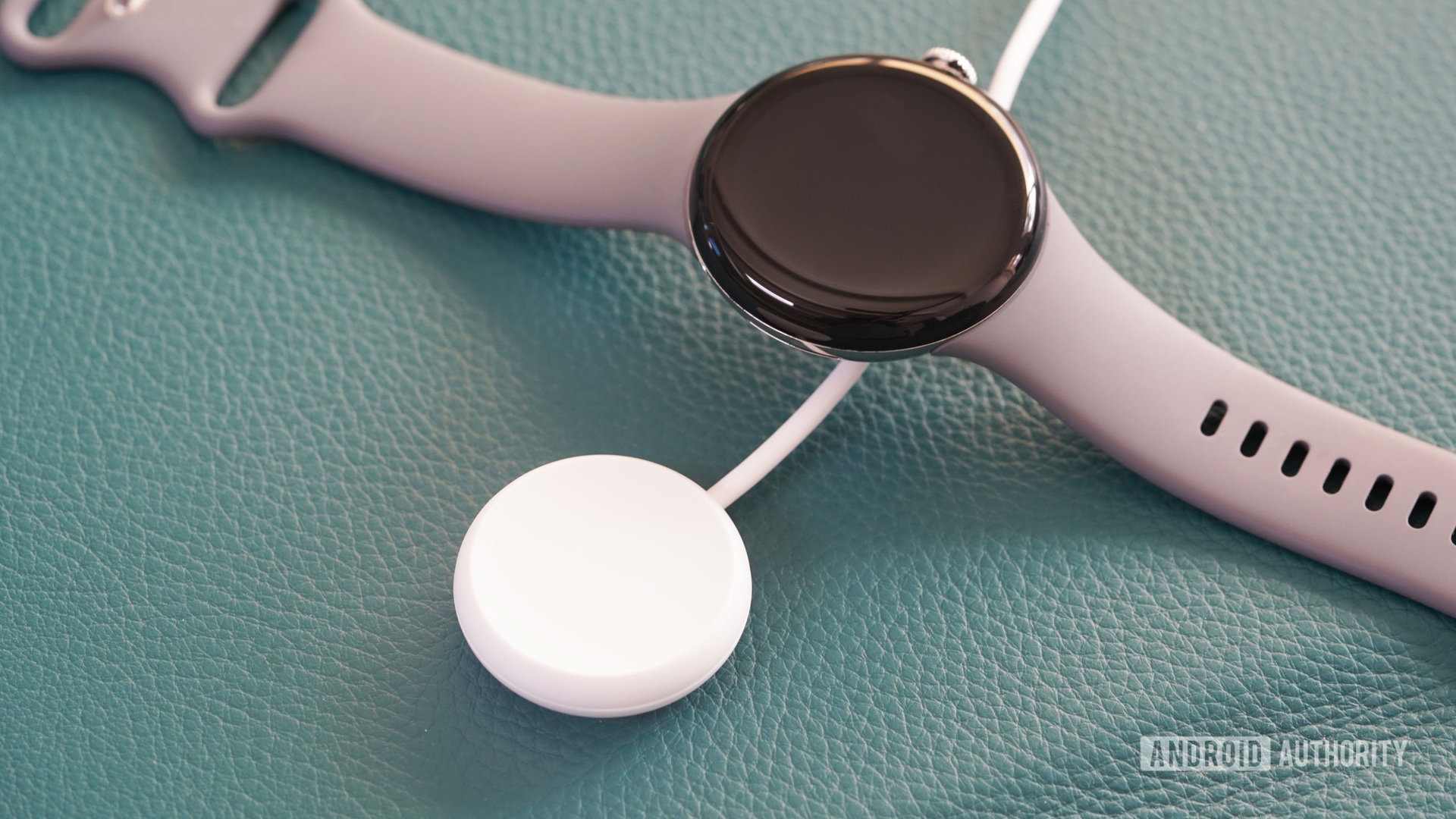 A Google Pixel Watch rests along side its USB-C charging cable.