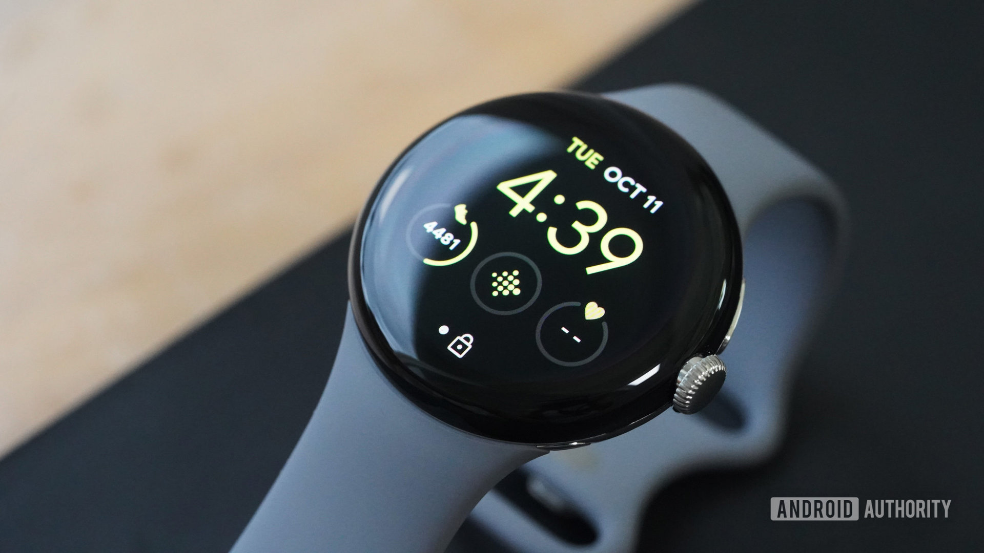 The Google Pixel Watch resting on a yoga mat displays the user's activity statistics on the default watch face.