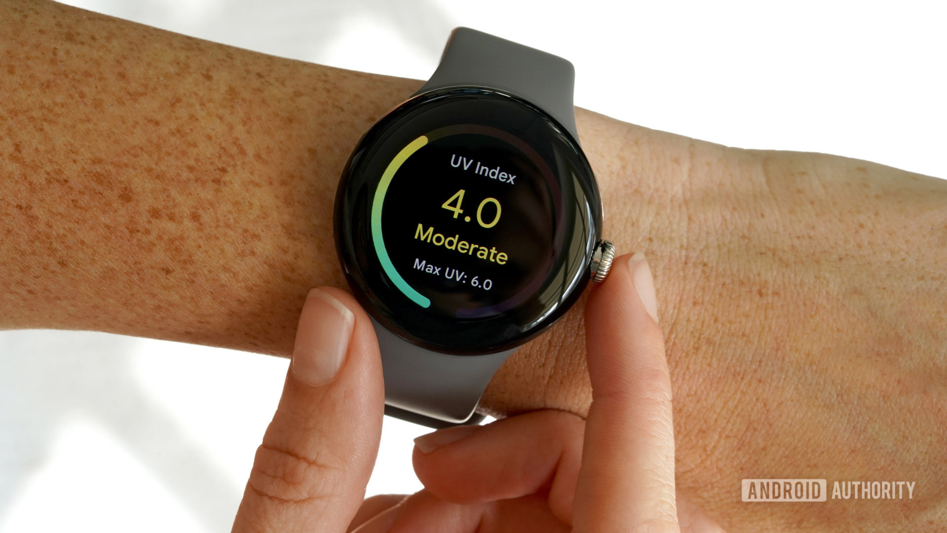 A Google Pixel Watch on a user's wrist displays the UV index tile.