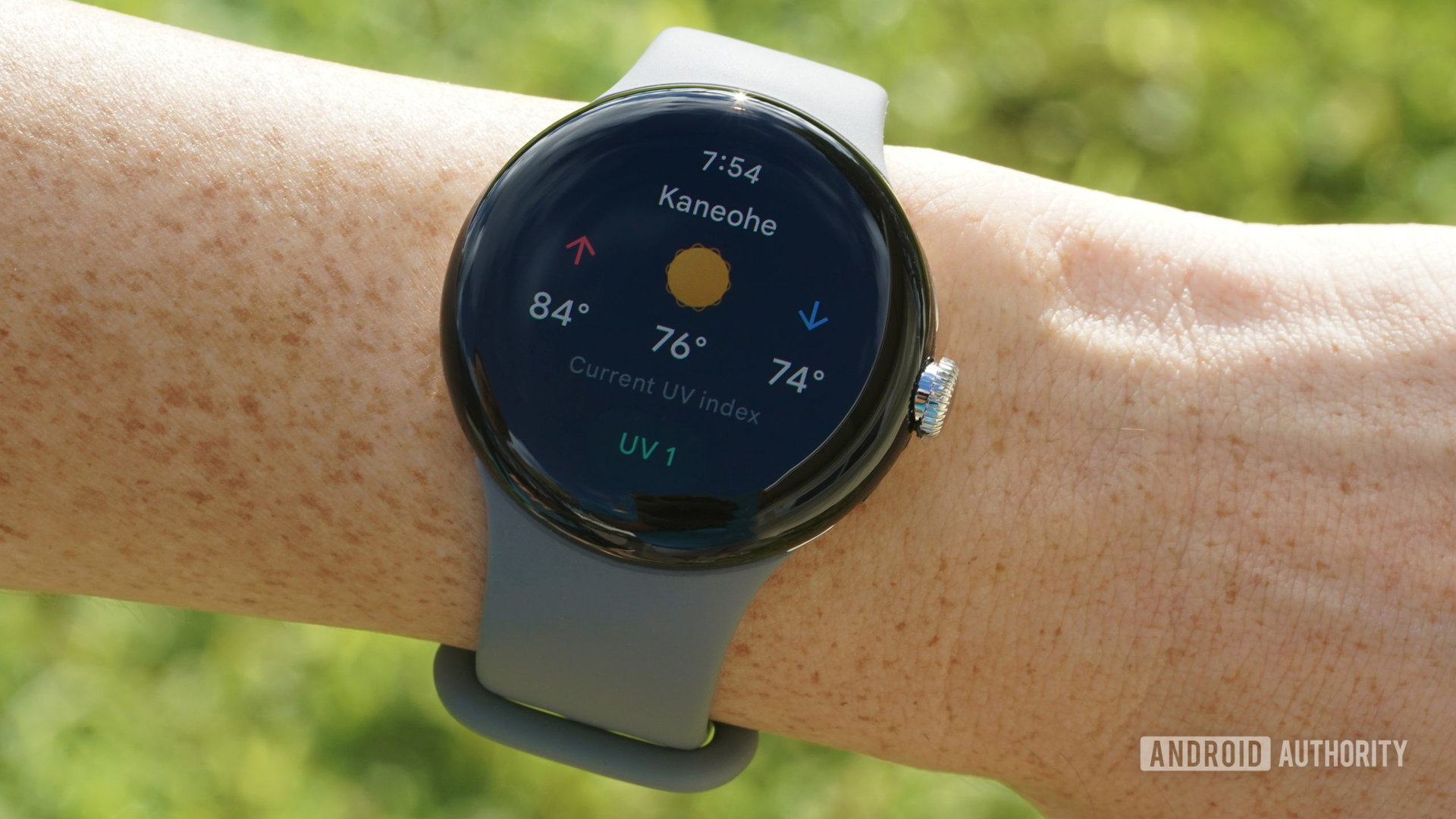 A Google Pixel Watch on a user's wrist displays weather details including the UV index.