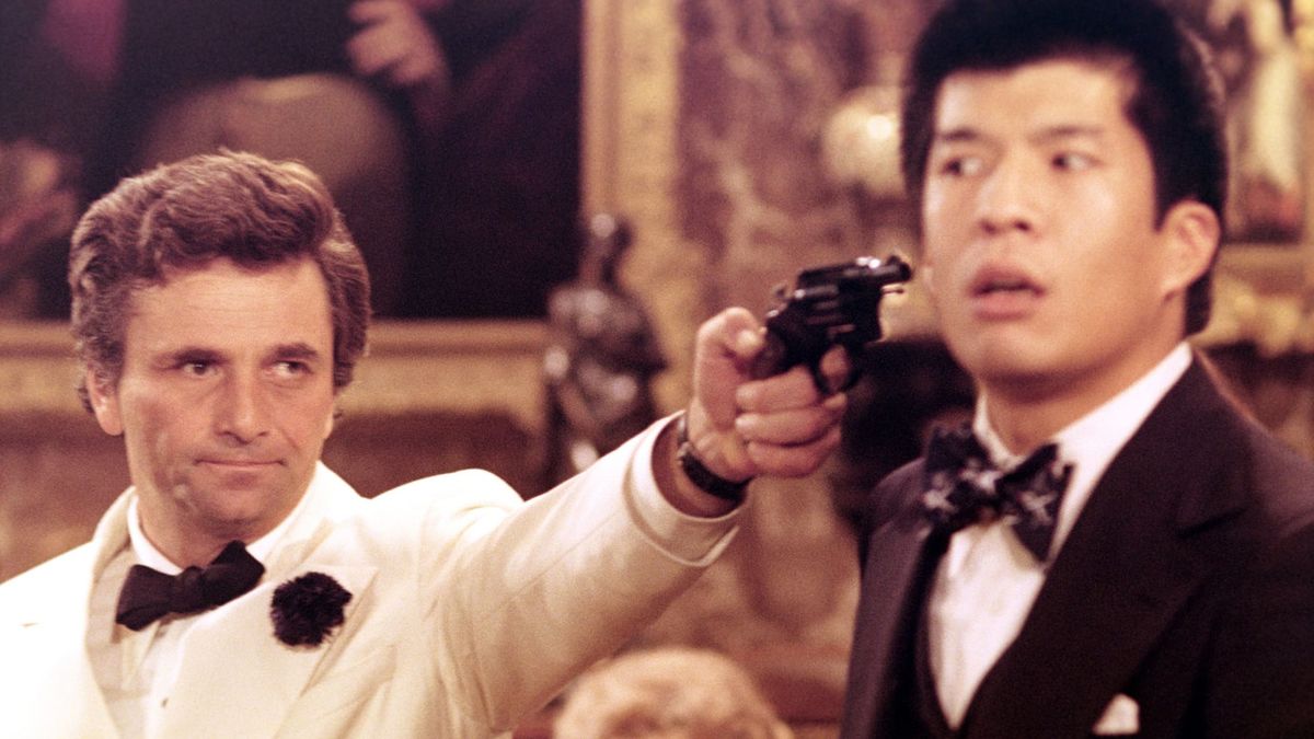 Peter Falk aims a gun at a man's head in Murder by Death