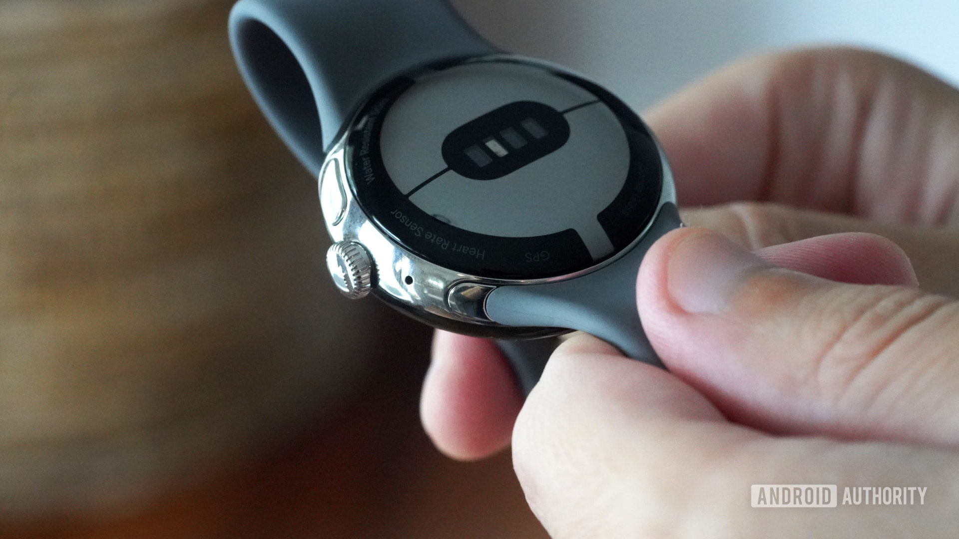 Un utilisateur tient sa Google Pixel Watch en main, illustrant comment trouver le bouton de retrait du bracelet.