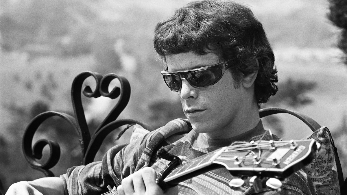 A black and white still of Lou Reed playing a guitar in The Velvet Underground - best apple tv plus movies