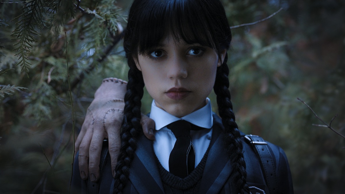 Jenna Ortega as Wednesday Addams with a severed hand on her shoulder in in Wednesday